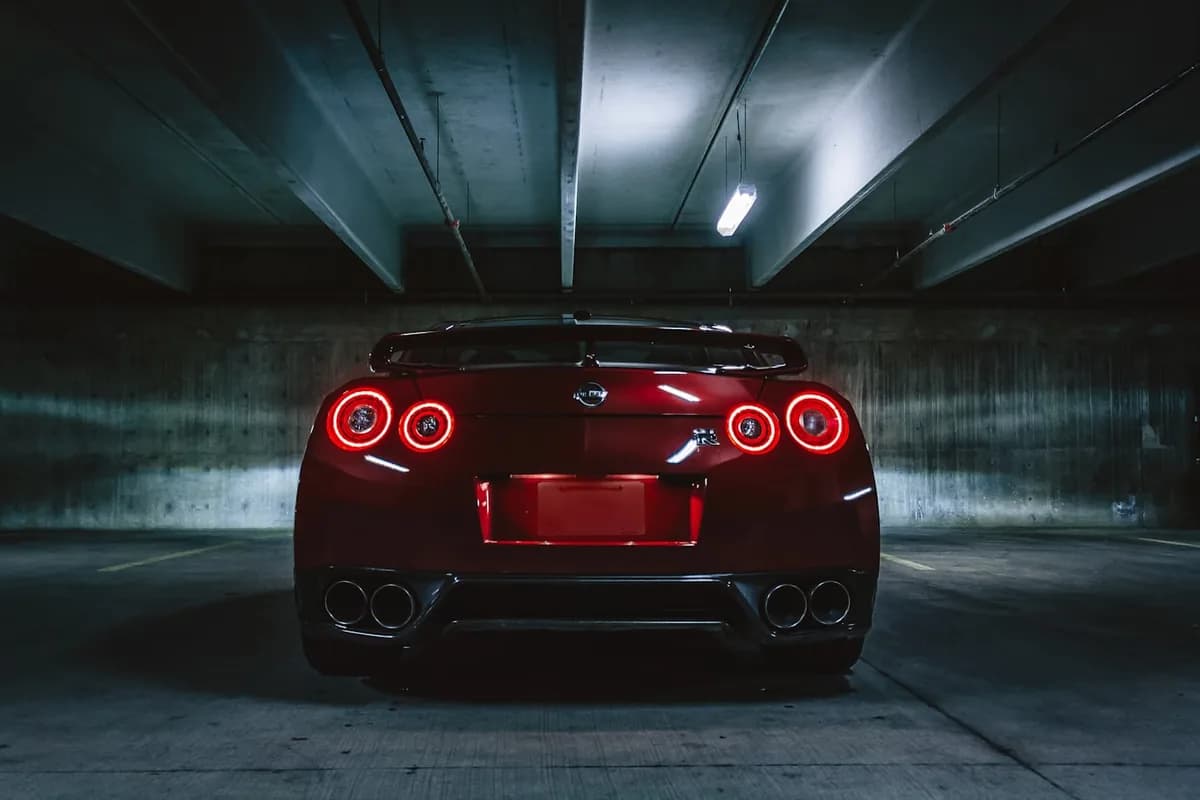 A performance car in a dark car park, tail lights glowing