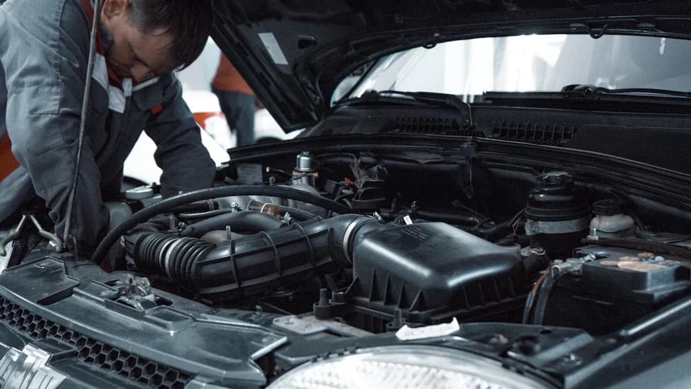 A laptop plugged into a car during coding and feature retrofit work