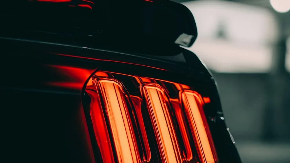 The glowing tail light of a performance car in a dark car park